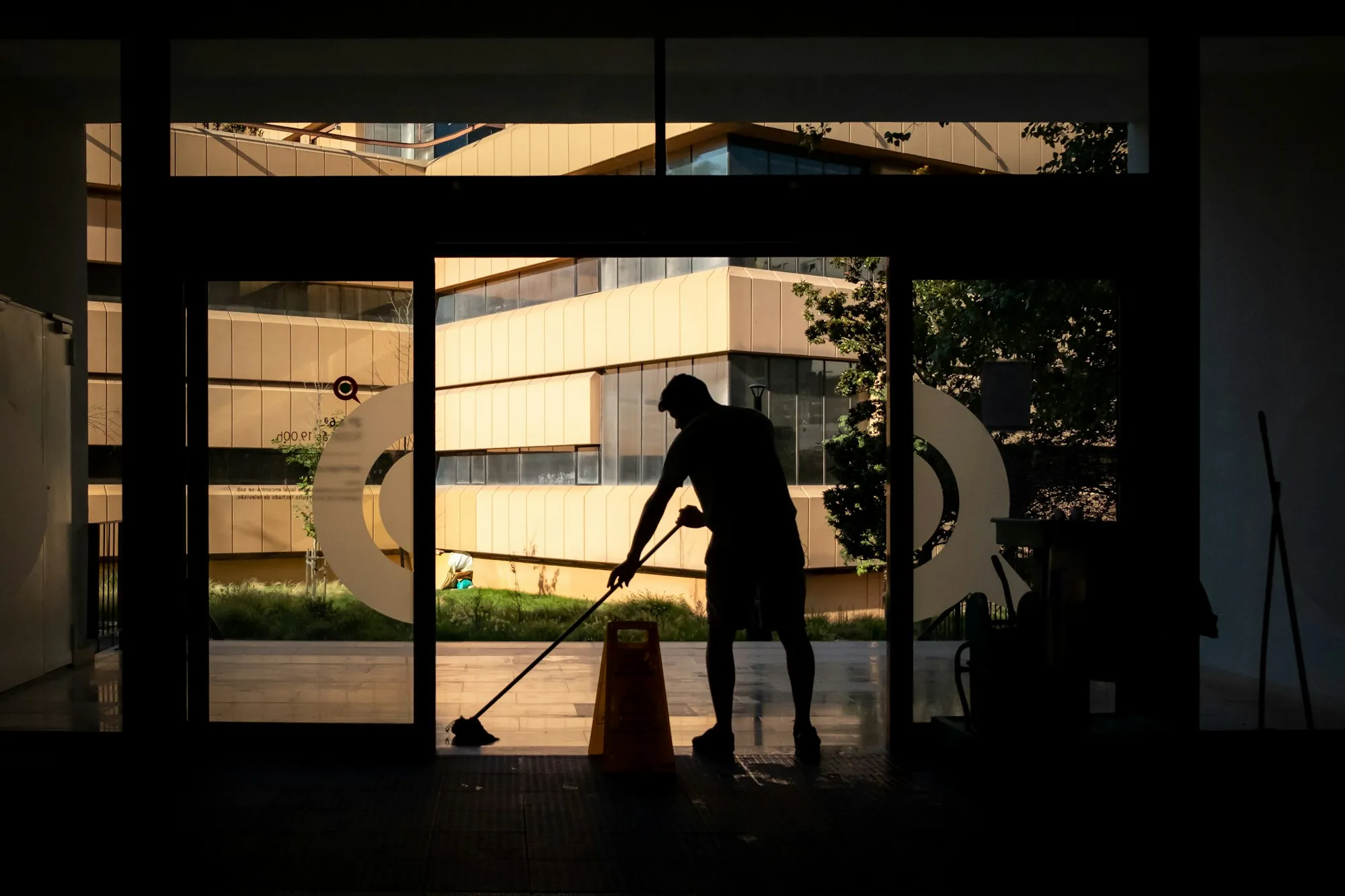 Silhouette of a cleaner mopping a lobby at night